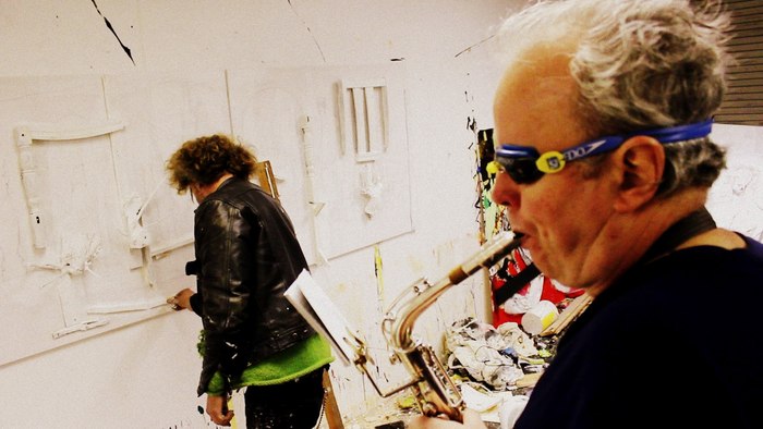 Mark Summers plays saxophone while Jonny paints